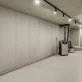 Empty concrete basement with sump pump and drainage system installed on the right wall